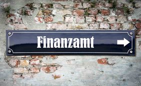 Straßenschild mit Aufdruck Finanzamt auf einer alten Steinmauer