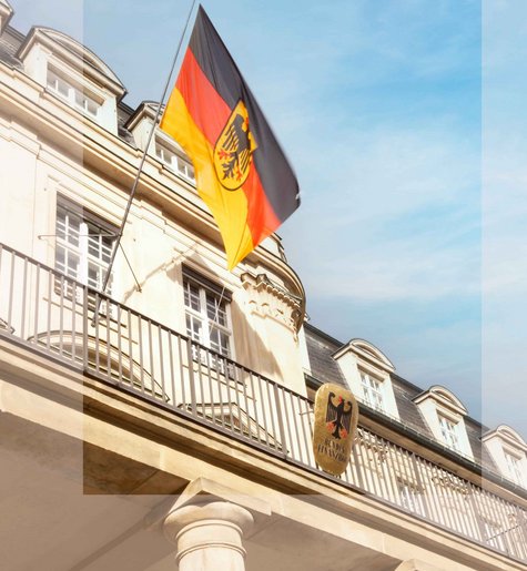 Portal des Bundesfinanzhofs mit wehender Deutschland-Fahne vor blau-weißem Himmel