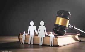 Schreibtisch mit Holzhammer, Buch und Papiergirlanden-Familie