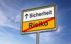 Verkehrsschild mit Aufschrift Sicherheit mit Pfeil nach oben auf weißem Untergrund, darunter Risiko rot durchgestrichen auf gelbem Grund 