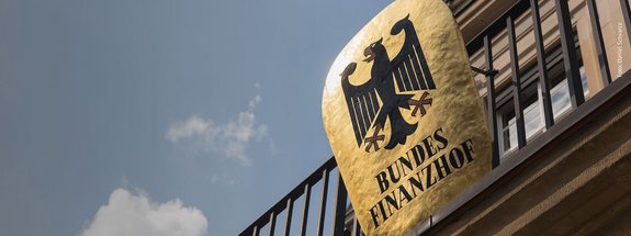 Blick von unten auf goldenes Bundesfinanzhof-Wappen mit Bundesadler am Balkon des Gebäudes