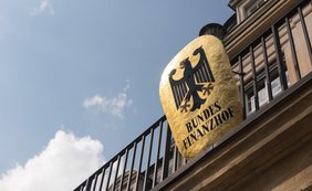 Blick von unten auf goldenes Bundesfinanzhof-Wappen mit Bundesadler am Balkon des Gebäudes